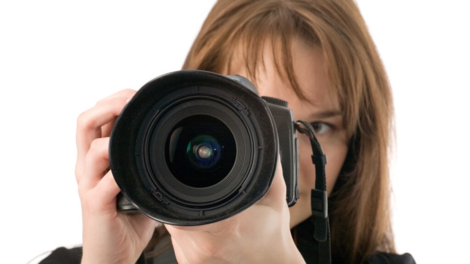 Kvinna som håller upp en kamera framför ansiktet.